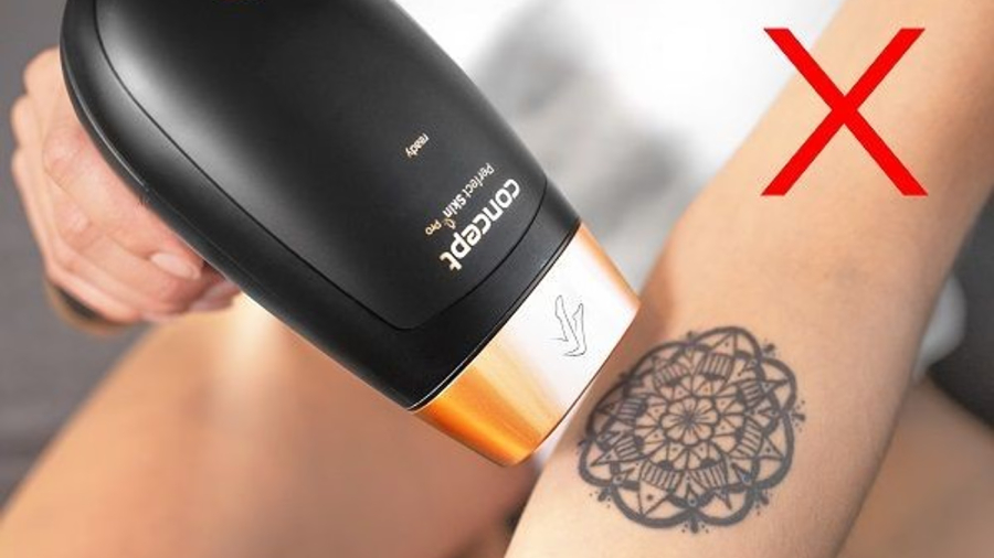 Detailní pohled na přikládání hlavice fotoepilátoru Concept Perfect Skin PRO anti age IL5020 k tetování na ruce s červeným symbolem X značícím zákaz používání.