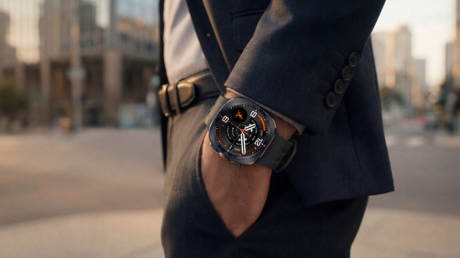 Muž v elegantním obleku kráčející městskou ulicí s chytrými hodinkami Galaxy Watch Ultra2 na ruce.