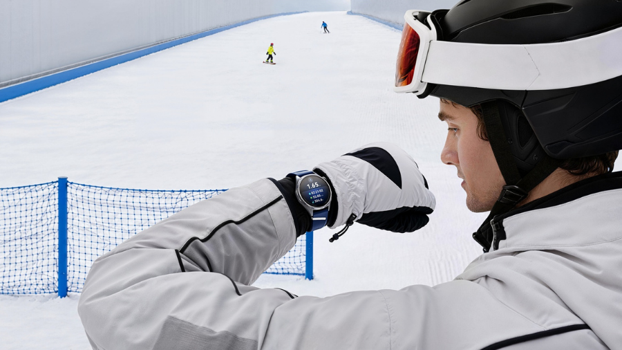 Lyžař v helmě a rukavicích kontroluje sportovní statistiky na hodinkách Huawei Watch GT 7 na sjezdovce.