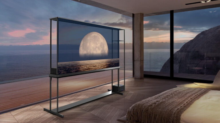 Průhledná televize LG SIGNATURE OLED T zobrazená v luxusní ložnici s výhledem na moře při západu slunce. Transparentní obrazovka stojí na minimalistickém černém stojanu a zobrazuje motiv velkého měsíce nad mořskou hladinou, přičemž skrze displej je vidět venkovní krajina.