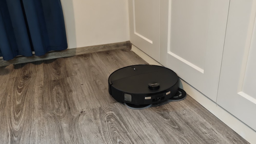 Robotický vysavač Roborock Qrevo Edge 2 při mopování podlahy podél stěny a nábytku v interiéru.