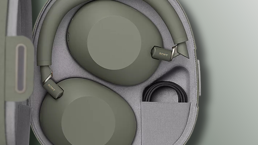 Detailní pohled na nová bezdrátová sluchátka Sony WH-1000XM6 v olivově zelené barvě, která jsou složená uvnitř ochranného přenosného pouzdra. Světle šedé textilní pouzdro má přesně vytvarované vnitřní přihrádky, ve kterých bezpečně leží otočené náušníky s viditelným logem SONY a vedle nich je stočený černý propojovací kabel.