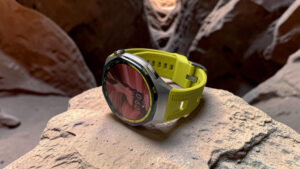 Detailní záběr na chytré hodinky Huawei Watch GT 7 Pro se sportovním žlutozeleným řemínkem položené na kameni uvnitř skalní jeskyně.