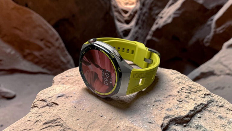 Detailní záběr na chytré hodinky Huawei Watch GT 7 Pro se sportovním žlutozeleným řemínkem položené na kameni uvnitř skalní jeskyně.