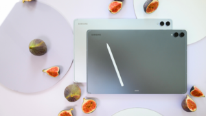 Dva tablety řady Samsung Galaxy Tab S12 v šedé a stříbrné variantě s dotykovým perem S Pen položeným na horním tabletu, obklopené rozkrojenými fíky.