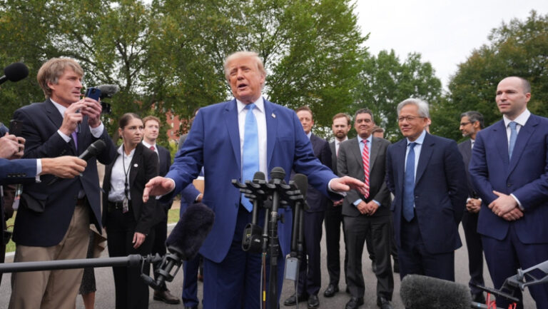 Donald Trump mluví na tiskové konferenci před novináři, zatímco za ním stojí manažeři technologických firem a probíhá debata o tom, jak se změní umělá inteligence.
